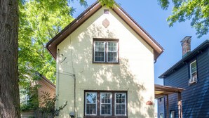 A two-story house with a gabled roof, a front porch, and a visible chimney.