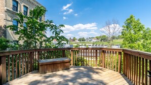 A wooden deck with a bench, overlooking a river and buildings.