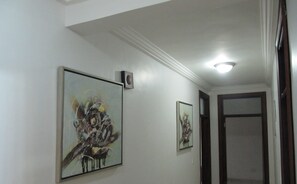 A hallway with two framed artworks on the walls and a ceiling light.