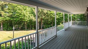 Ein überdachter Balkon mit Blick auf eine Rasenfläche und Bäume.