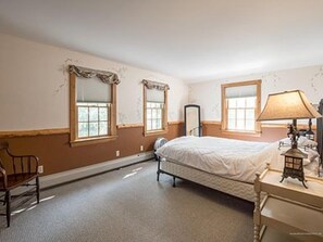 Ein Schlafzimmer mit Bett, Stuhl, Nachttisch und Lampe.