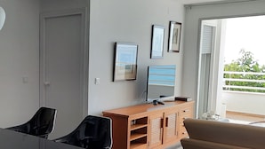 A modern living room with a large black table, a beige sofa, and a wooden entertainment unit with framed pictures. - Apartment in front of the beach and with free parking in the same building. (Altea)