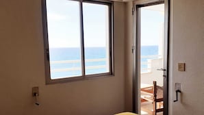 A room with a bed, a window with a view of the sea, and a door leading to an outdoor area. - Apartment in front of the beach and with free parking in the same building. (Altea)
