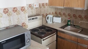 A compact kitchen with a microwave, stove, toaster, and sink.