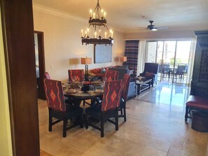 Uma sala de jantar com um candelabro, uma mesa posta para seis pessoas e seis cadeiras dispostas ao redor.