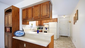 Una cocina con armarios de madera, un refrigerador blanco y un plato decorativo azul sobre la encimera.