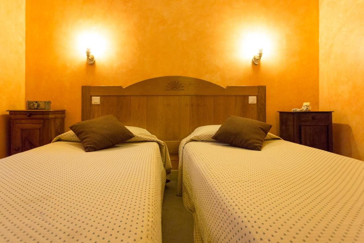 Une chambre avec deux lits, chacun doté d’une tête de lit en bois et d’une table de chevet.