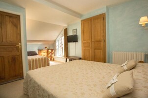 Un dormitorio con cama, armario de madera, televisor en la pared y ventana.