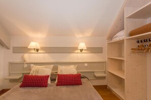 A bedroom with a bed, two bedside lamps, a wardrobe, and a shelf with folded clothes. - Logis Hôtel Etchemaïté (Doué-en-Anjou)