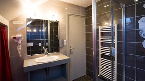 Ein modernes Badezimmer mit Duschkabine aus Glas, einem weißen Waschbecken und einem Handtuchhalter.