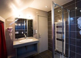 Un baño moderno con cabina de ducha de vidrio, un lavamanos blanco y un perchero para toallas.
