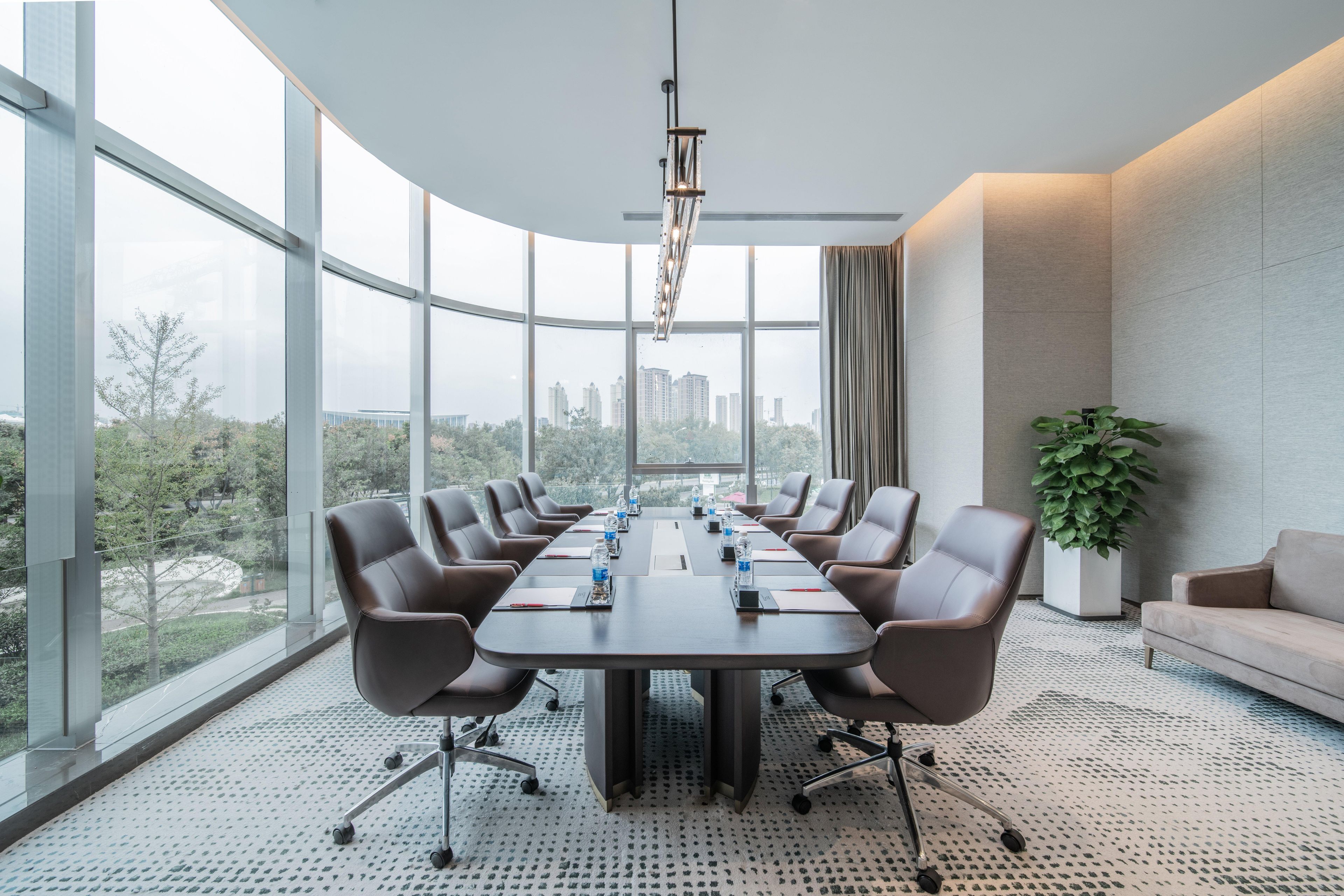 A conference room with a large table, chairs, a plant, and a city view.