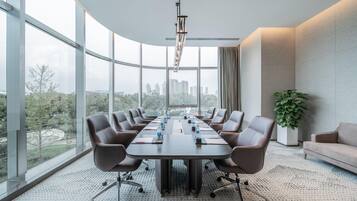A conference room with a large table, chairs, a plant, and a city view.