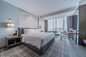 A modern hotel room with a large bed, a desk, and a view of the city. - Hualuxe Xi'an Chanba (Xi'an)