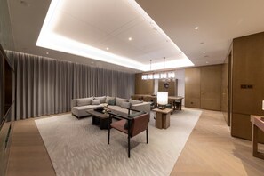 A modern living room with a sofa, coffee table, and dining area. - Hualuxe Xi'an Chanba (Xi'an)