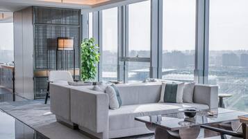 A modern living room with a sofa, a coffee table, and a large window offering a city view.