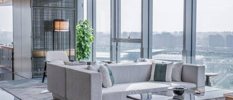 Uma sala de estar moderna com um sofá, uma mesa de centro e uma janela grande com vista para a cidade.