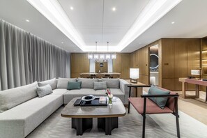 A modern living room with a sectional sofa, a coffee table, and a dining area with a table and chairs.