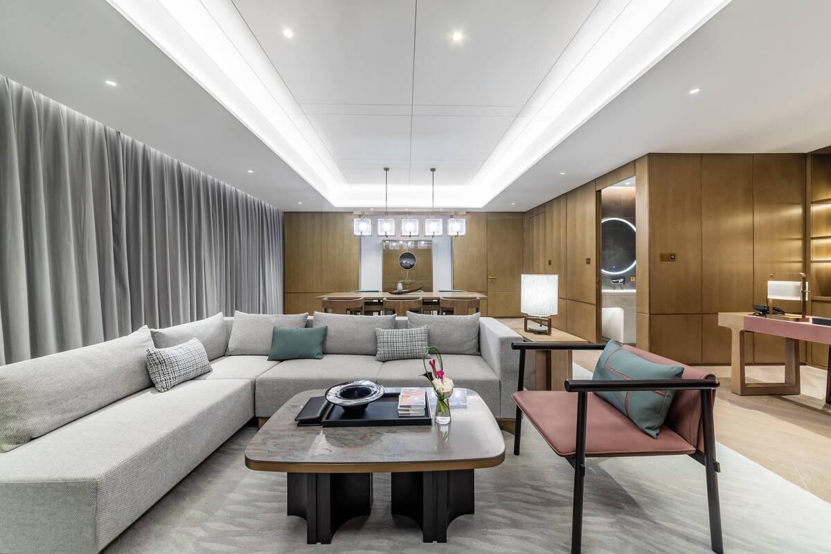 A modern living room with a sectional sofa, a coffee table, and a dining area with a table and chairs.