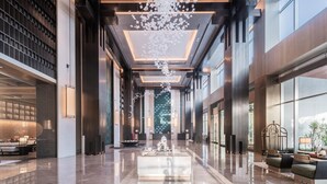 A spacious lobby with a central reception desk, seating areas, and large windows.