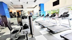 Ein Fitnessstudio mit Laufbändern, Kraftgeräten und einer Spiegelwand.