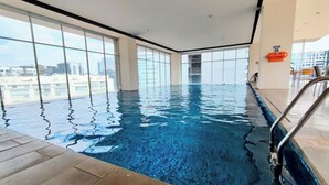 Ein Hallenbad mit klarem, blauem Wasser, großen Fenstern und Blick auf die Stadt.