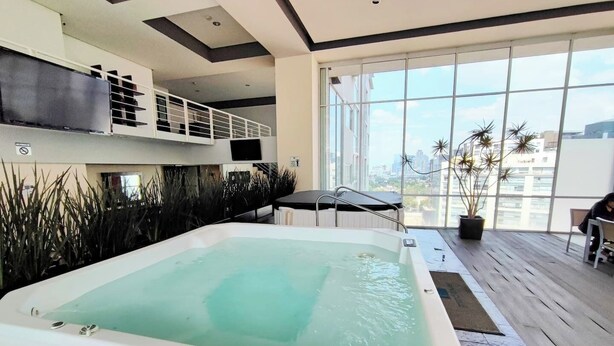 Ein moderner, überdachter Pool mit Blick auf die Stadt durch große Fenster.