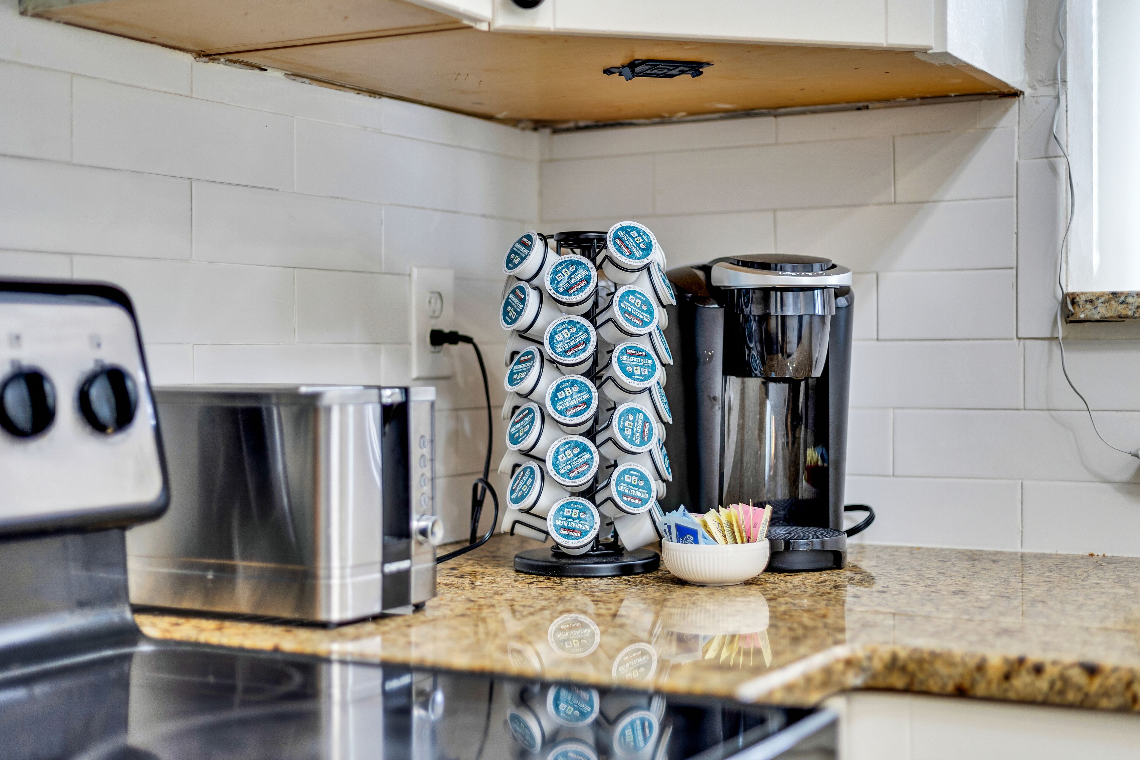 A kitchen with a coffee maker, toaster, and a stack of coffee pods.