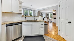 Una cocina moderna con armarios blancos, lavavajillas de acero inoxidable y encimera de granito.