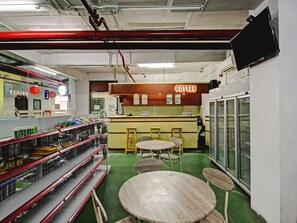 A coffee shop interior with a counter, stools, and shelves stocked with snacks. - Super OYO 90245 Tridasa (Medan)