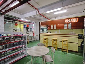 A coffee shop interior with a counter, stools, and a table. - Super OYO 90245 Tridasa (Medan)