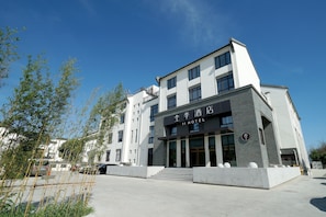 A modern hotel building with a prominent entrance, multiple floors, and a clear sky.