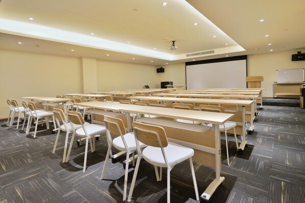 A conference room with multiple tables and chairs, a projector, and a whiteboard.