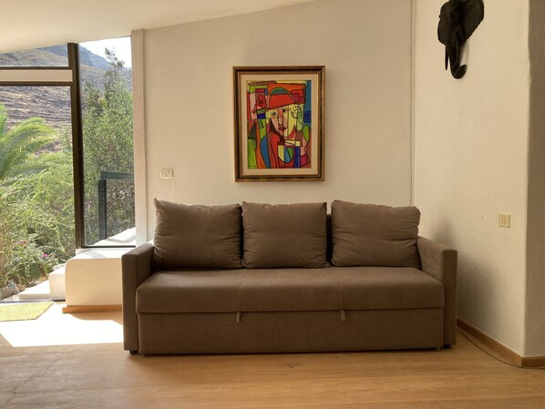 A modern living room with a beige sofa, a colorful abstract painting, and a mounted elephant head sculpture.