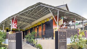 A covered outdoor area with a metal roof, potted plants, and a gated entrance. - OYO 3509 Pondok Yanti (Ciater)