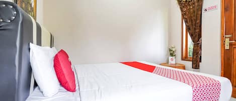 Una cama con ropa de cama blanca y roja, un cabecero de madera y una mesita de noche con una planta.