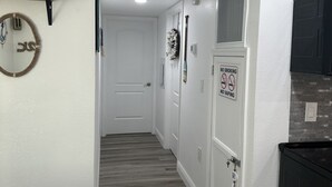 A hallway with a wooden floor, white walls, and a door with a 'No Smoking' sign. - Buckhead ridge fishing headquarters (Okeechobee)
