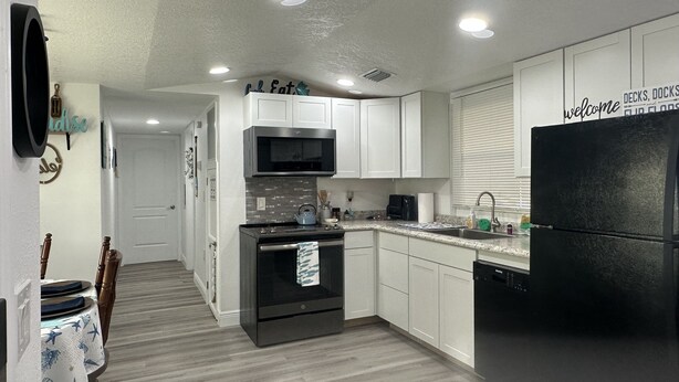 A modern kitchen with white cabinets, a black refrigerator, and a microwave. - Buckhead ridge fishing headquarters (Okeechobee)