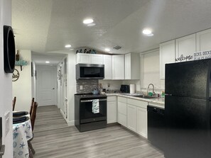 A modern kitchen with white cabinets, a black refrigerator, and a microwave. - Buckhead ridge fishing headquarters (Okeechobee)