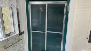 Une salle de bain avec une porte de douche en verre, des carreaux de marbre et un porte-serviettes en laiton.