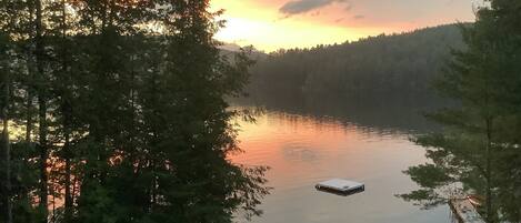 Eine Holzhütte am See mit einem Steg und einem kleinen Boot.