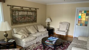 Un salon avec des canapés à motifs, une table basse avec des livres, un tapis décoratif et un tableau au mur.