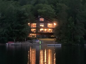 A multi-story house with a dock and boats, surrounded by dense trees. - Private Sandy Beach with 125 feet of lake frontage (Paradox)