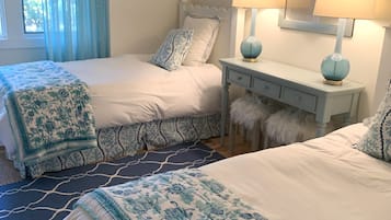 A bedroom with two beds, a nightstand, a lamp, and a framed starfish decoration.