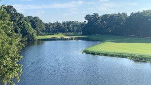 Näkymä järvelle, jonka taustalla on golfkenttä, edessä puinen terassi ja alueen ympärillä puita.