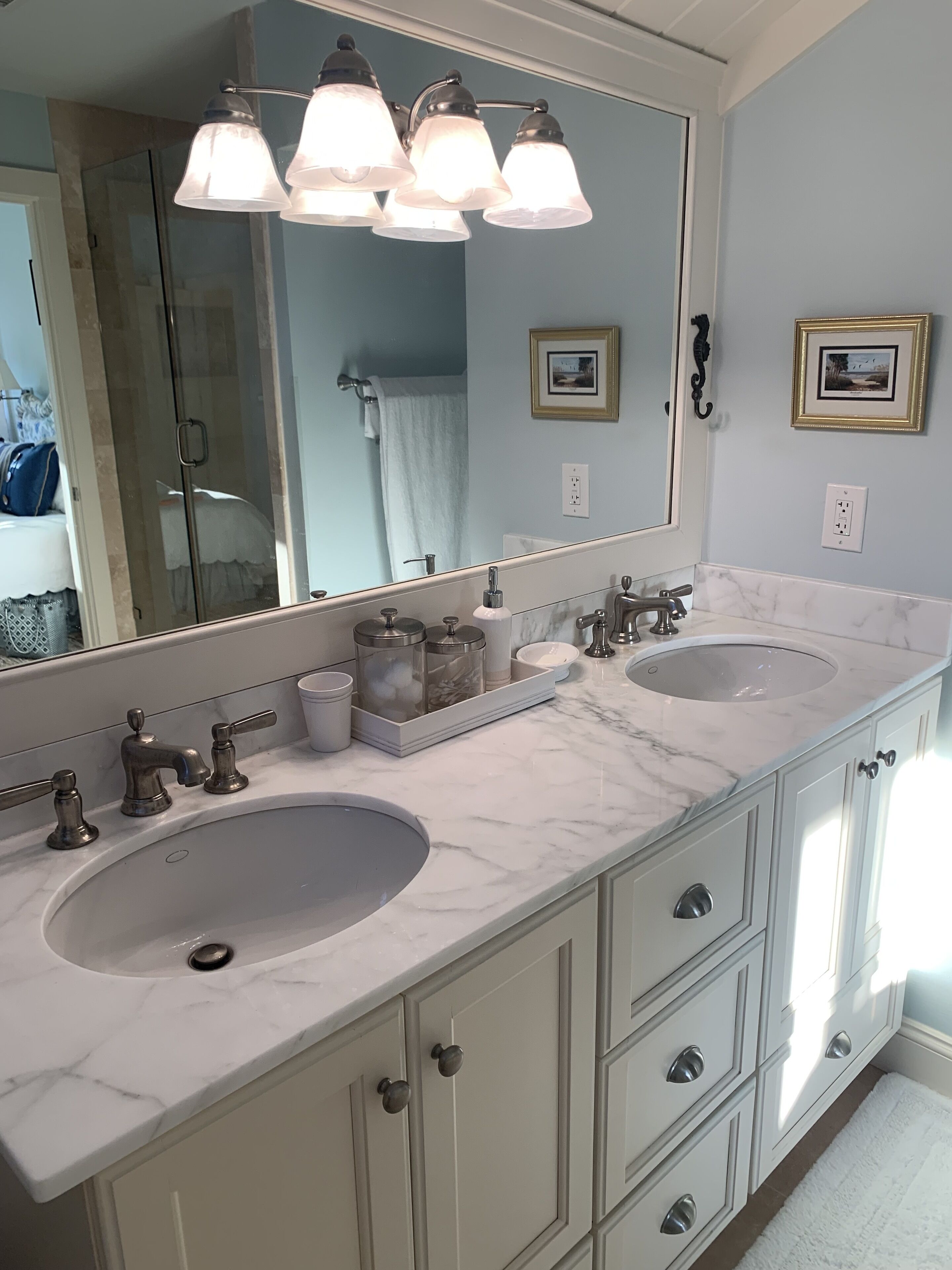 A bathroom with two sinks, a large mirror, and a vanity with drawers.