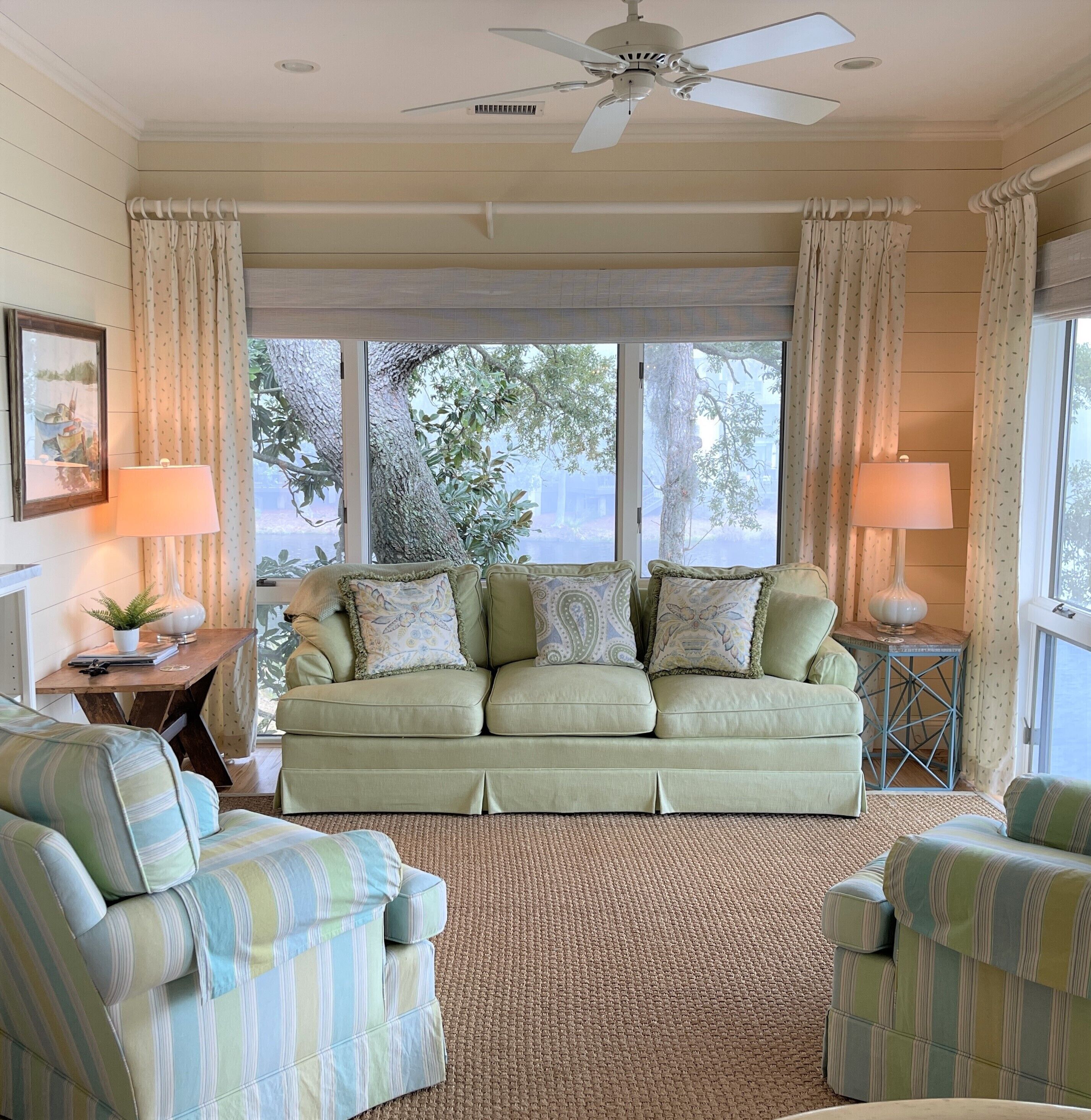 A cozy living room with a sofa, two armchairs, a side table, and a lamp.