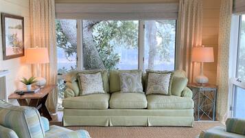 A cozy living room with a sofa, two armchairs, a side table, and a lamp.