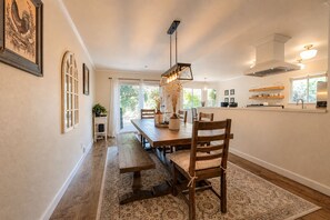 A dining area with a wooden table, chairs, and a hanging light fixture. - Spacious Oasis Hot Tub Backyard Garden 3BR/2BA (Sonoma)