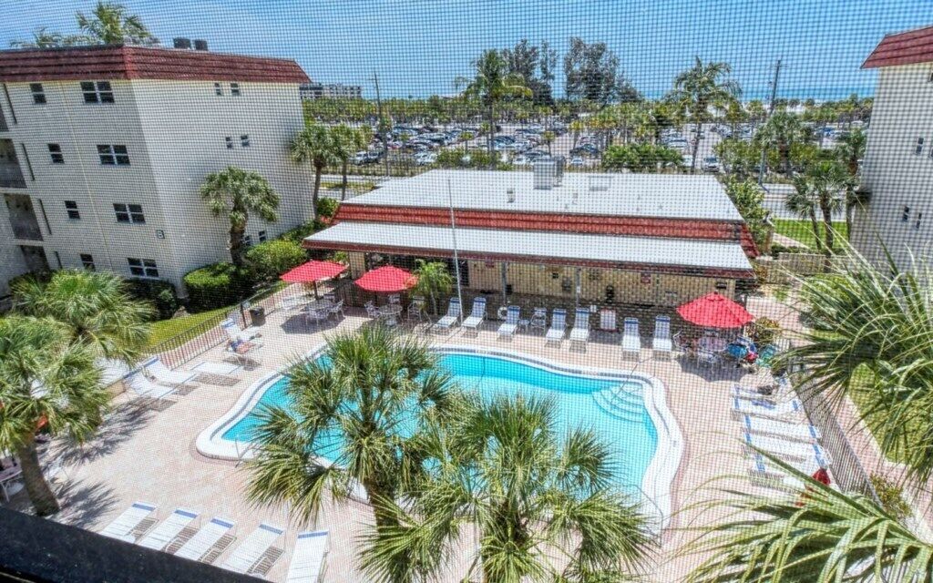 Ein Hotel mit Swimmingpool, umgeben von Palmen und Liegestühlen.